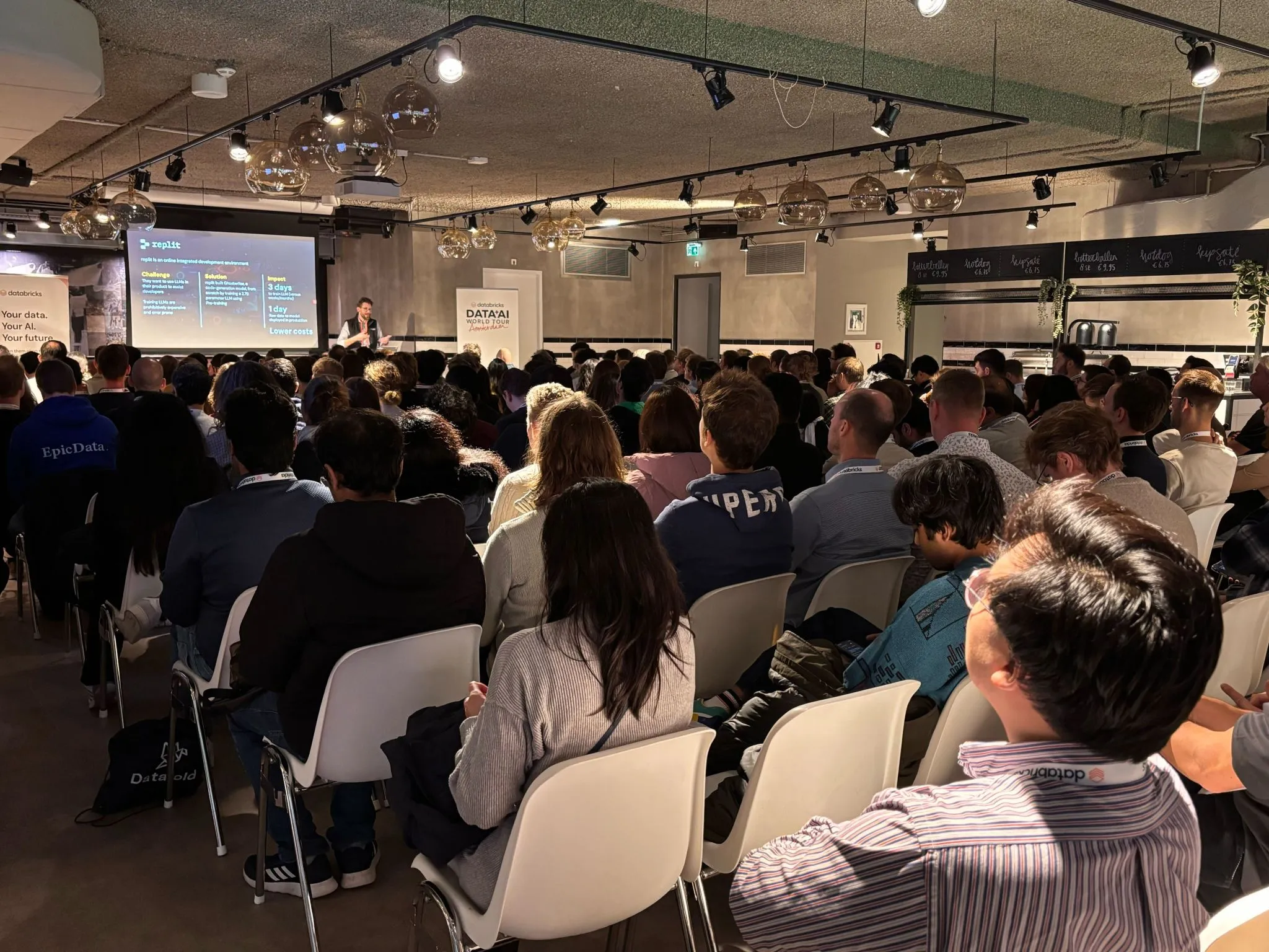 Romain on stage at Data + AI World Tour Amsterdam 2024, presenting to a packed room of about 200 people.